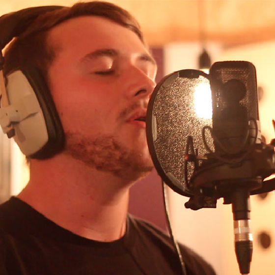 A man singing into a microphone in a studio.