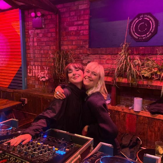 Two girls DJ'ing at a DJ Deck.