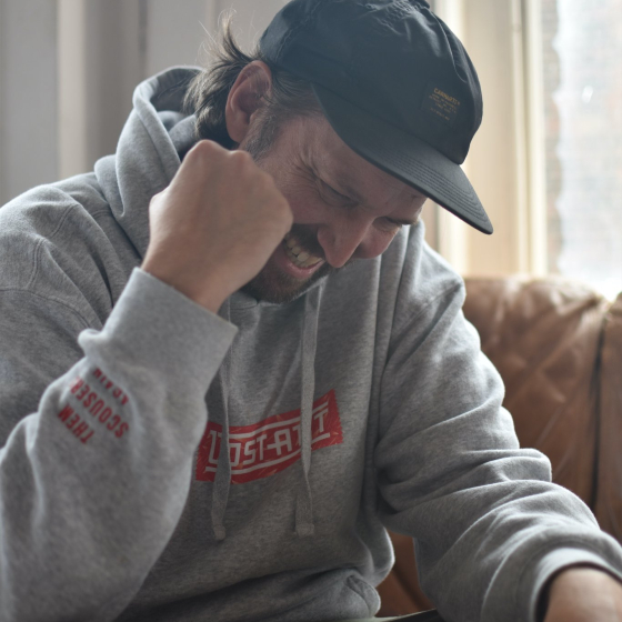 Paddy Quinn wearing a cap and a grey hoodie and smiling.