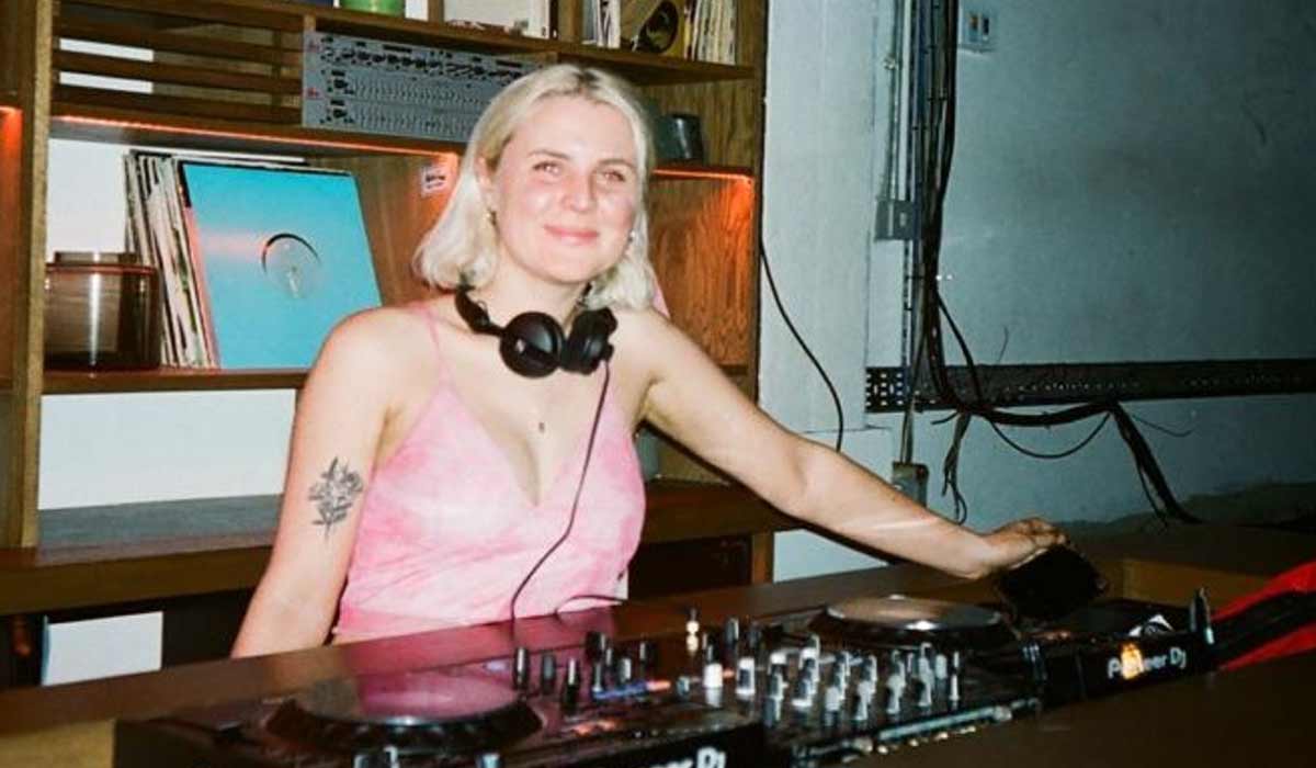 A film camera photo of a woman behind a DJ deck.