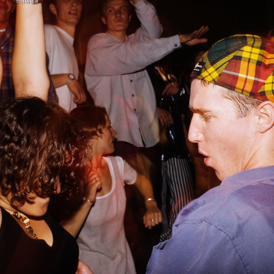 Man in a blue shirt and checked cap dancing next to a woman at the Cream nightclub.