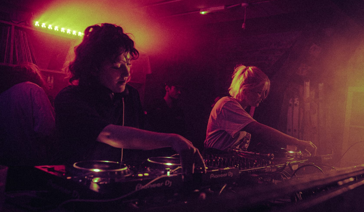 Two DJ's performing in a dimly lit venue.