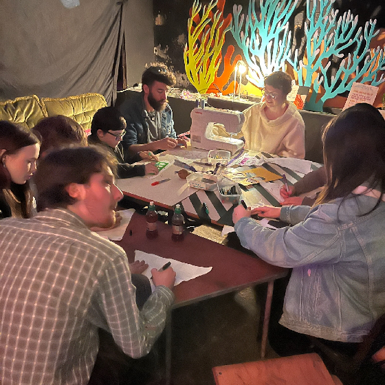 A group of people sat around a table partaking in a craft activity.