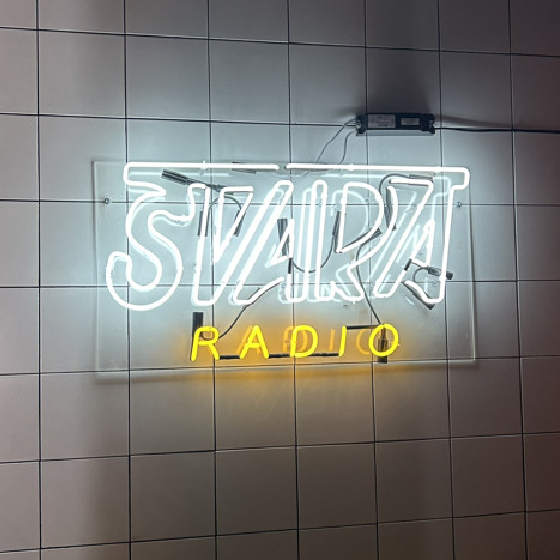 An image of a neon sign reading "SVARA RADIO" on white tiles.