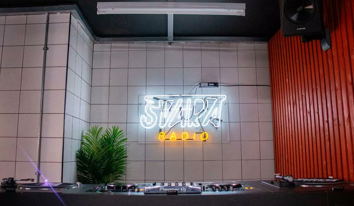 An image of a neon sign reading "SVARA RADIO" on white tiles.