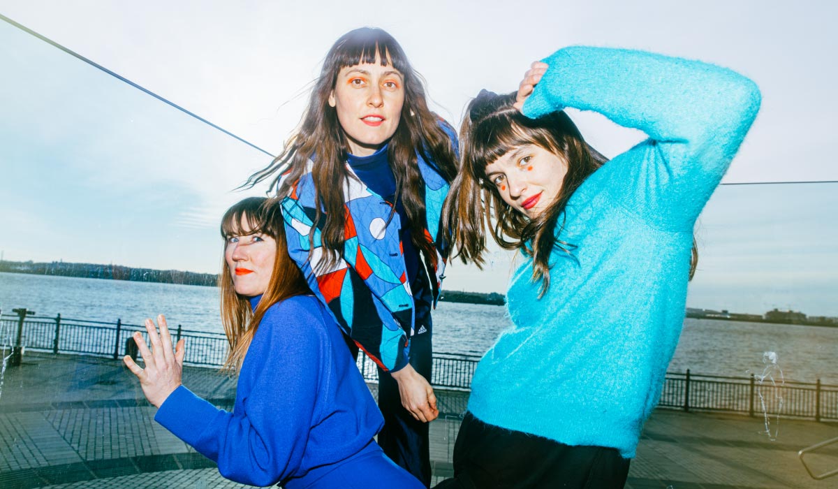 Three women in blue sweaters posing and smiling together.