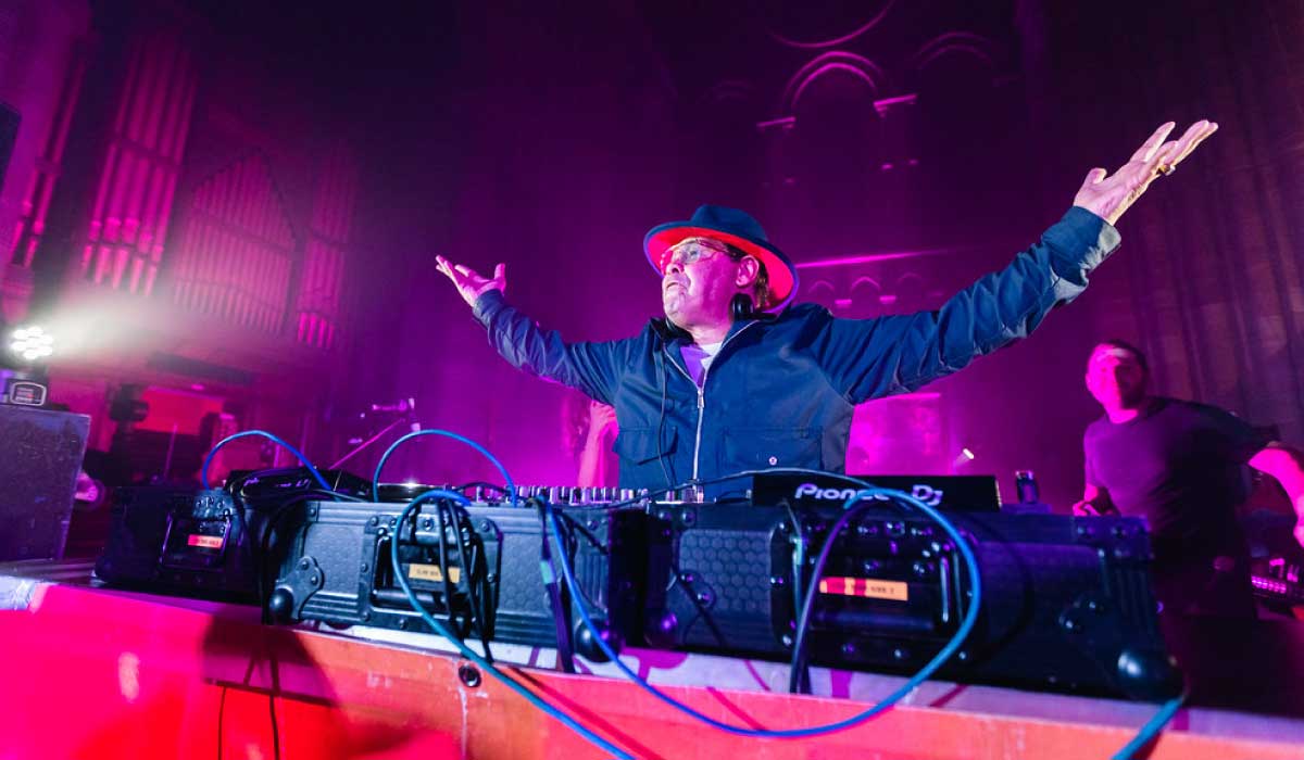 Craig Charles behind a DJ deck with his arms outstretched