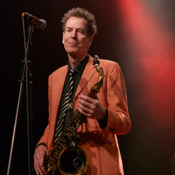 A man performing with a saxophone on tage