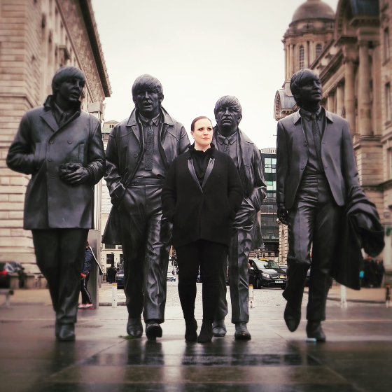 A woman posing with a statue of The Beatles