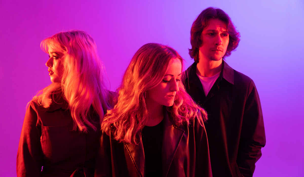 Three people stood under pink and purple lighting