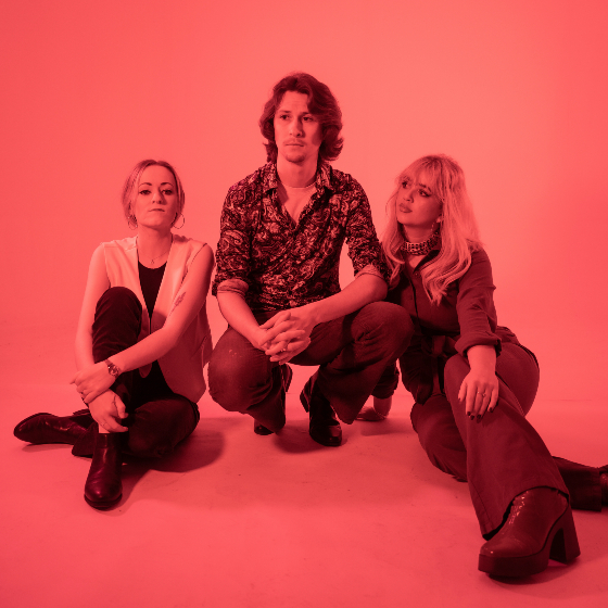 Three people sat together under red lighting