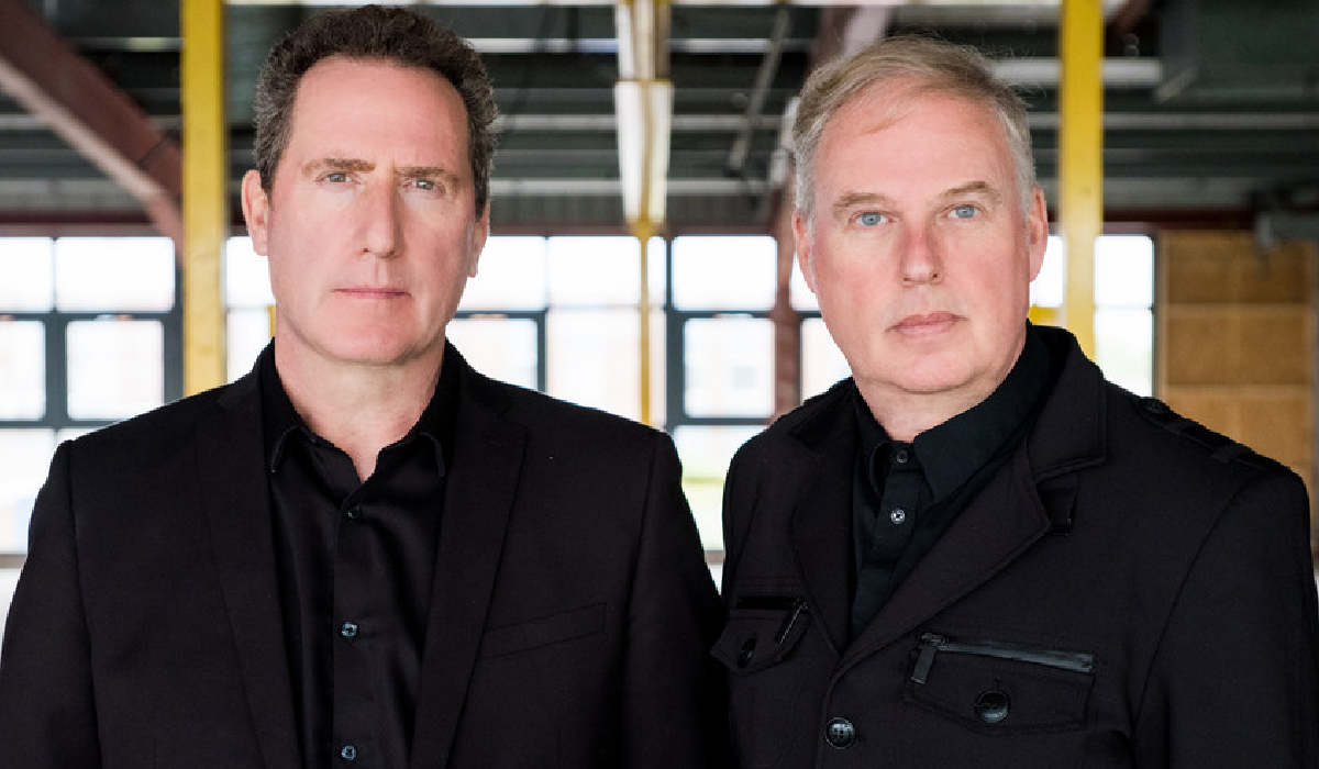 An image of two men stood together, both wearing black