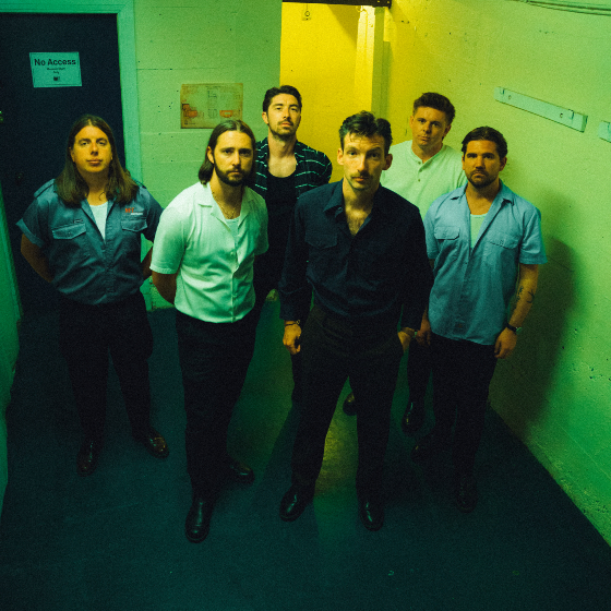 Six individuals stand in a corridor under a green light