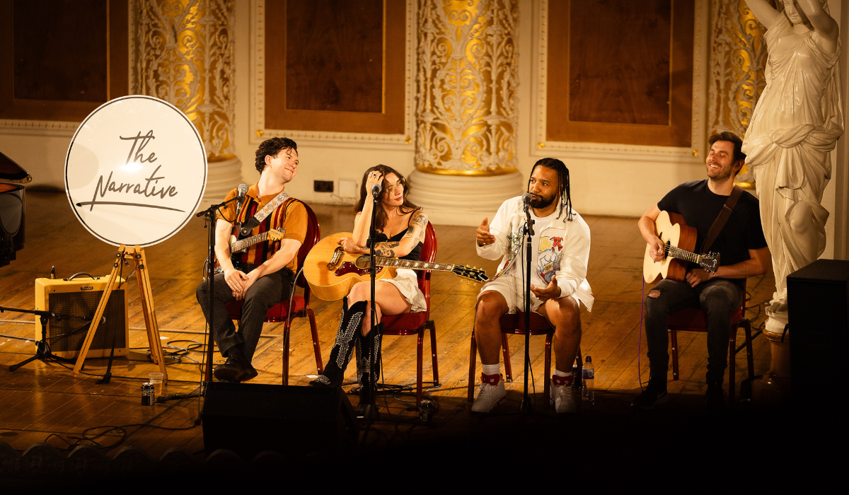 Four people sittingin a row some holding instruments.