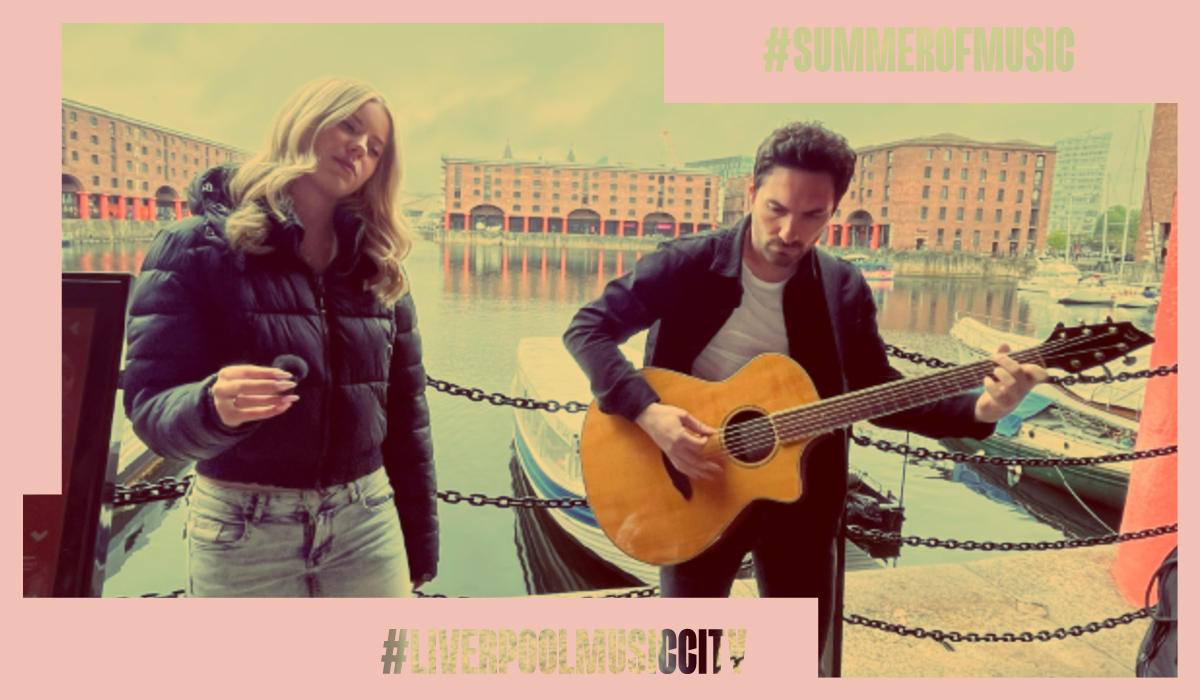 Singer and acoustic guitarist performing at Liverpool’s Albert Dock, with waterfront buildings and boats in the background. Text reads '#SUMMEROFMUSIC' and '#LIVERPOOLMUSICCITY'.