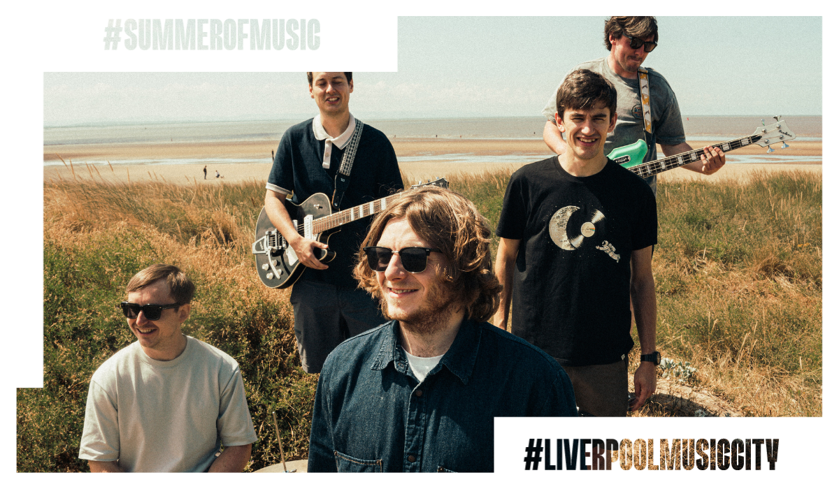 five people on a sanddune on a beach some are holding instruments.
