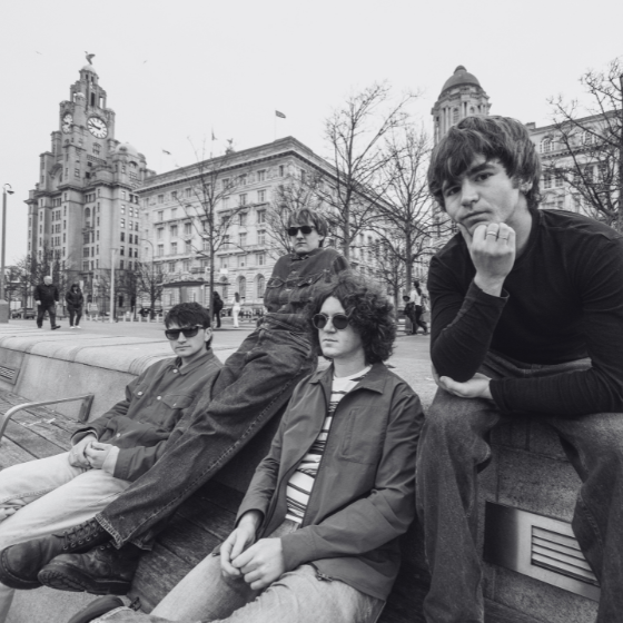 Four people sitting on the Pier Head in Liverpool. 