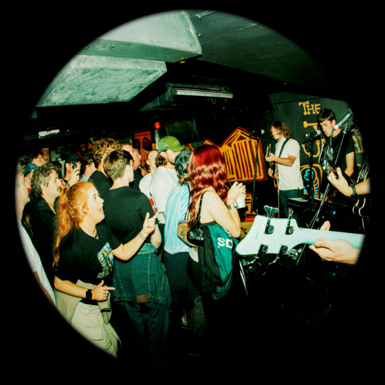 A photo of a gig in a basement with a crowd of people. 