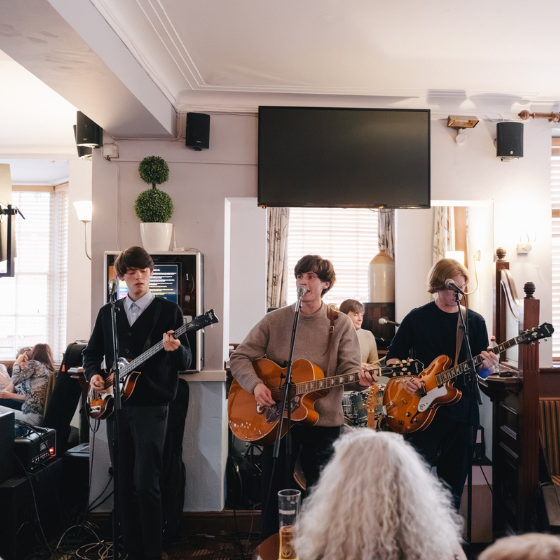 Three people holding guitars singing in a pub. 