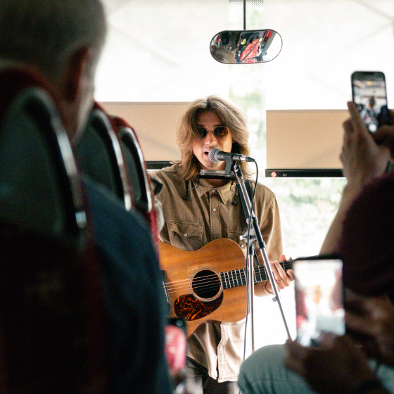 A person playing guitar on a coach stood at the front of the bus.
