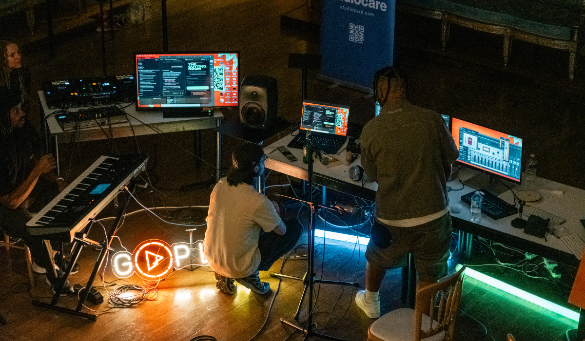 Two people sitting at screens recording music.