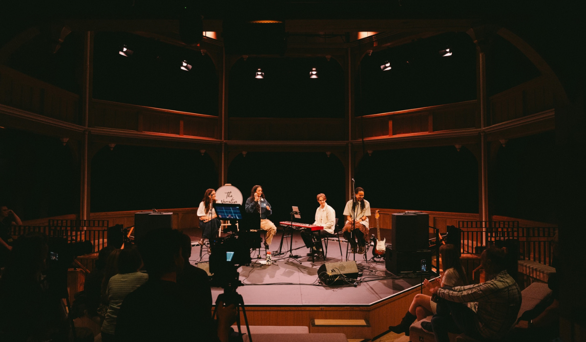 A group of people on a stage in a theatre with instruments.